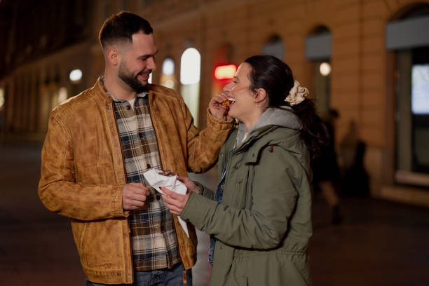 istock Couple Sharing a Bag of Chestnuts on a Cold Winter Night 1493714423