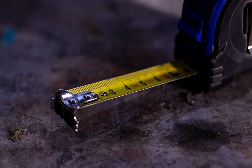 A measuring ruler rests on a dusty floor illuminated by a light source