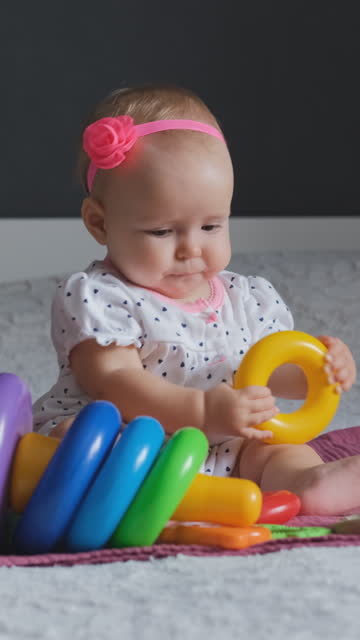 Cute baby girl playing colorful pyramid