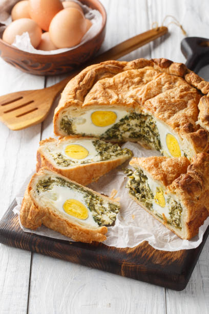 istock Torta Pasqualina traditional Italian savory pie with spinach, chard, ricotta and whole eggs closeup on the wooden board. Vertical 1493719004