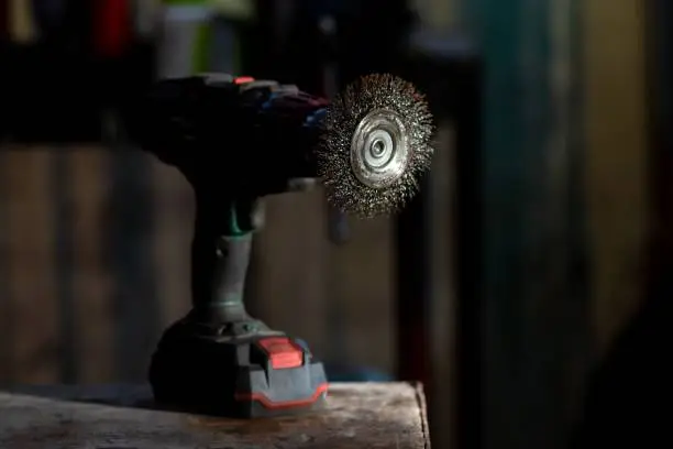 A close-up image of a drill and several drill bits laid on top of a wooden table surface