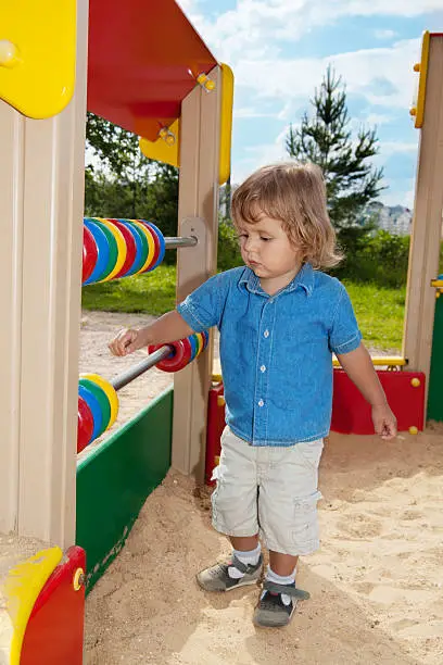 blond toddler playing with counting-frame on the playground