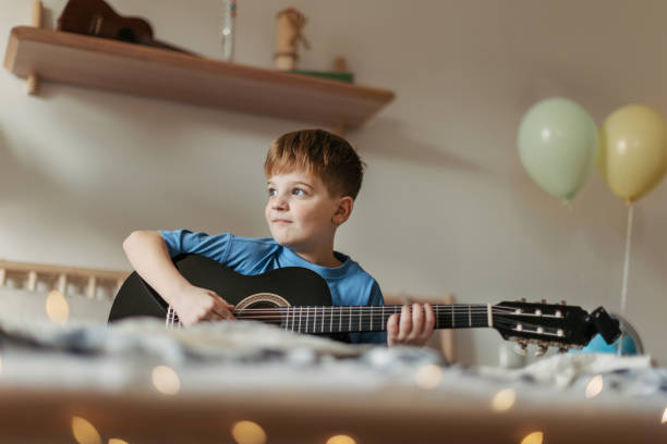istock Happy boy playing on the guitar in his room. 1493728398