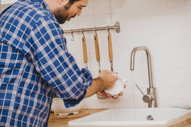 istock Man doing chores cleaning dishes cup at home kitchen sink holiday activity. 1493729677