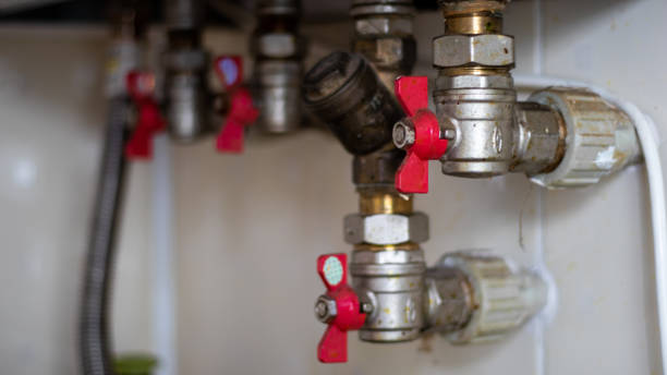 Hidden water taps for connecting a gas boiler on a tiled wall. Plumbing connections for a domestic double-circuit gas boiler. Pipes of the heating system. Installing a gas boiler with red taps grifos de agua ocultos para conectar una caldera de gas en una pared de azulejos. conexiones de fontanería para caldera de gas doméstica de doble circuito. tuberías del sistema de calefacción. instalación de una caldera de gas con grifos rojos.