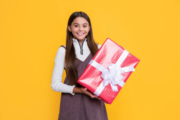istock cheerful girl with present box on yellow background 1493730918