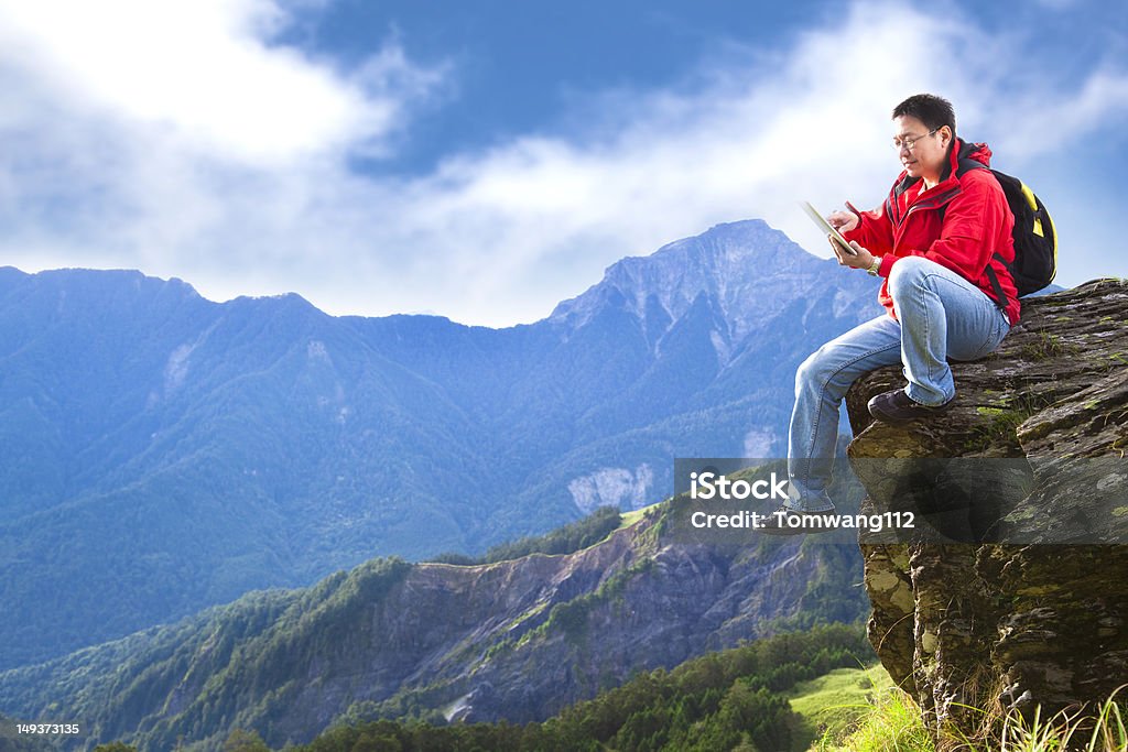 Giovane uomo con touch pad sulla cima di montagna - Foto stock royalty-free di Adulto