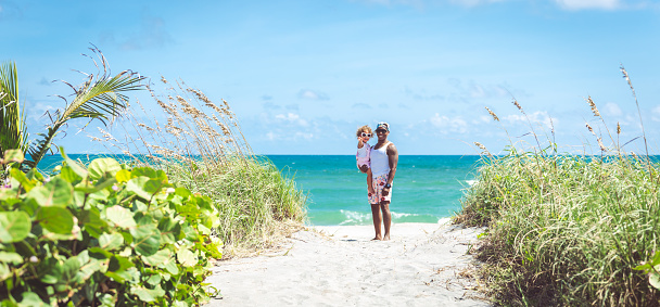 Adorable toddler and her dad enjoying a day on the beach in Florida