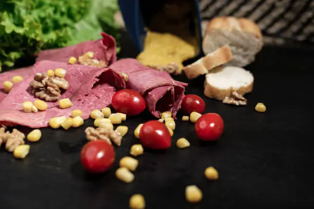 Photo of Deli meat cold cut  with vegetables, cherrry tomatoes, sweet corn, walnuts and lettuce salad leaves, french baguette