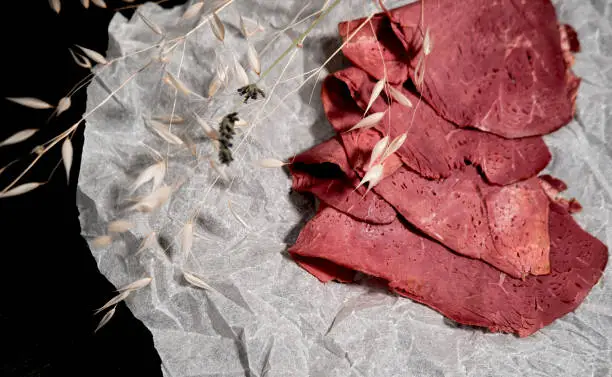 Photo of cold cut platter, deli meat  as easy quick luncheon snack on cooking paper dark background