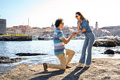 Man proposing to his girlfriend by the sea edge on a beautiful sunny day