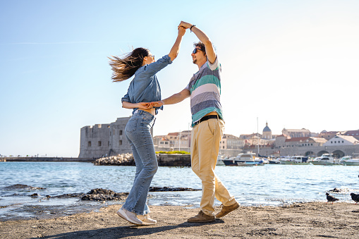 Young couple in love dancing by the sea edge on a beautiful sunny day