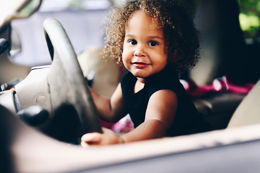 Cute little girl pretending to drive the family car