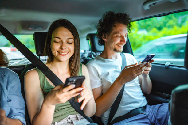 istock Young Adults Using Phone While Riding In The Backseat Of The Car 1493746084
