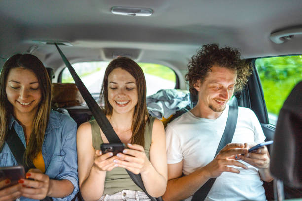 istock Young Adults Using Phone While Riding In The Backseat Of The Car 1493746428