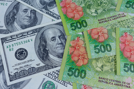 Billetes de 100 dólares junto con billetes de 500 pesos argentinos. photo