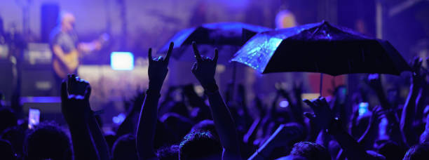 Carefree women having fun while dancing on a rain at music concert.