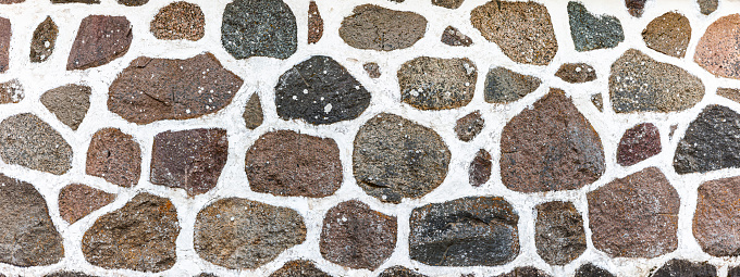 Natural stone wall made of granite stones and white mortar
