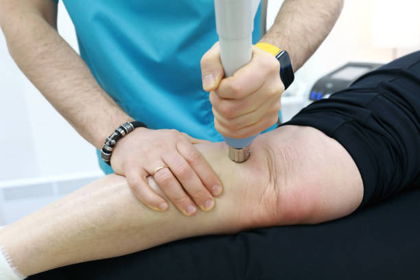 istock Osteopath treating knee to woman with shock wave therapy 1493762030