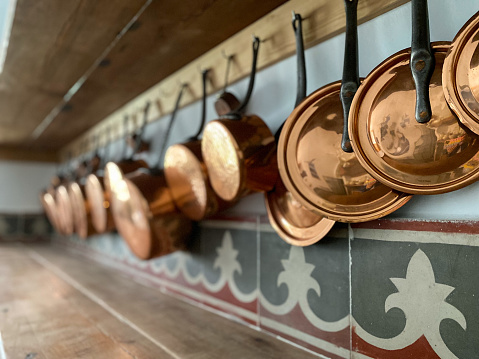 Antique brass saucepans hanging on the shelf in a rustic kitchen