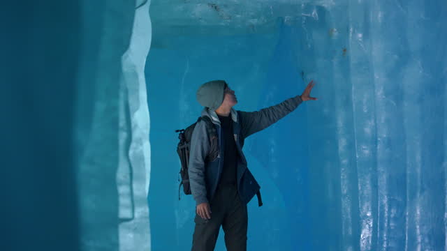 Young man exploring ice cave