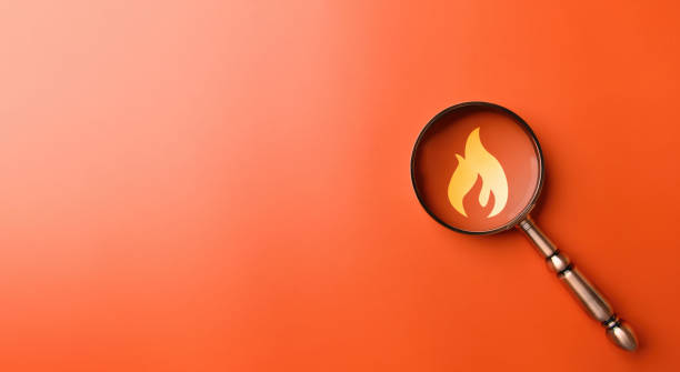 istock Fire surveillance inspection and fire fighting with magnifying glass on orange background. Fireman and conflagration concept. 1493768911