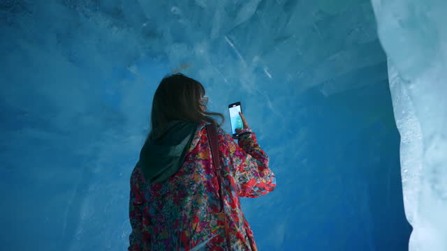 Women exploring and shooting video in ice cave