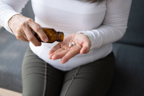 istock Close up view of old lady taking out the pills from the bottle while sitting on the sofa. 1493772694
