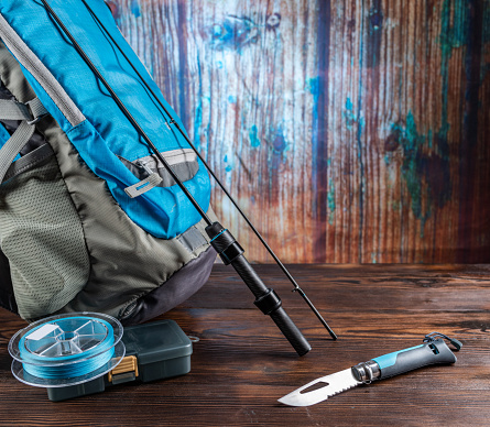 Tourist fisherman's set. Fishing rod and backpack. Fishing composition with spinning and knife. Front view.