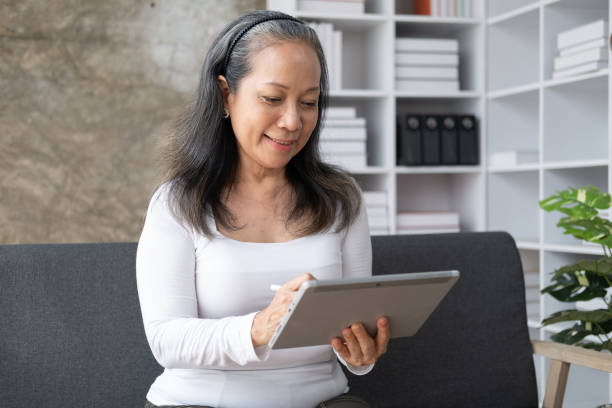 istock Beautiful senior woman relaxing on comfortable leather sofa with digital tablet. 1493774970