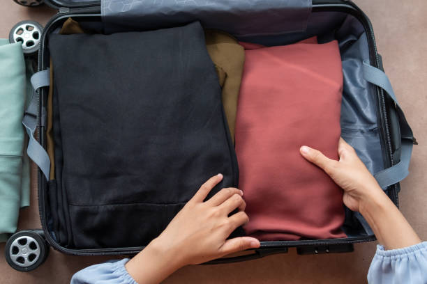 istock Asian woman putting clothes in a suitcase 1493777043