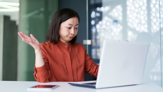 Frustrated Asian woman complaining about poor performance of computer program