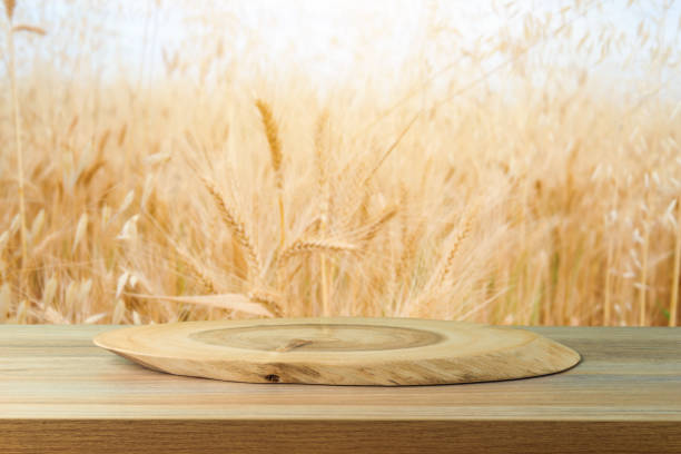 istock Empty wooden board log on table over wheat field background.  Harvest concept mock up for design and product display. 1493789298