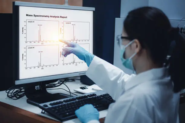 Photo of Scientist woman indicates the chromatogram of mass spectrometry analysis results of compounds.
