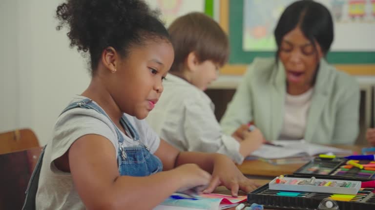 Girl drawing pictures in classroom at school.