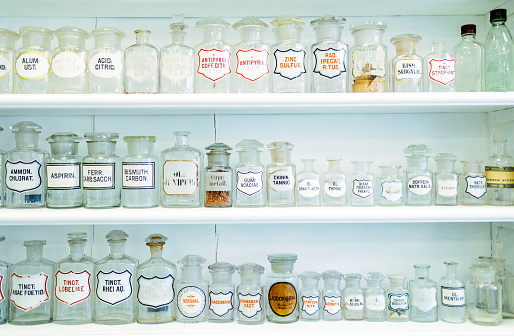 Chemicals for making medicine in historic pharmacy, glass bottles standing on shelves, labeled in Latin script
