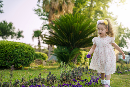 baby girl picking flowers for her mother outdoors. happy baby girl