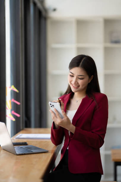 Young professional businesswoman using smartphone, having a phone call with her customer in the meeting room.