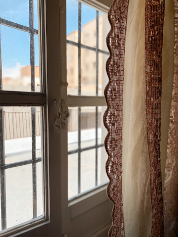 Rustic window at sunrise with handmade antique fabric hanging curtains