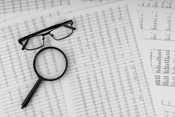 Magnifying glass and eye glasses on financial statement. stock photo