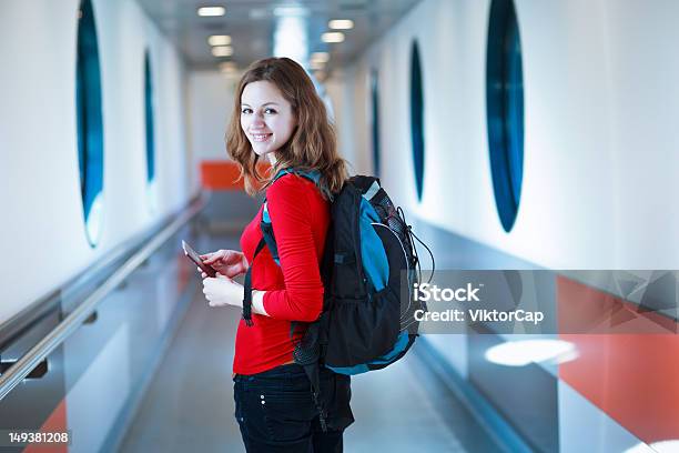 Woman In Red Shirt With Book Bag Boarding A Flight Stock Photo - Download Image Now - Passenger Boarding Bridge, Passenger, Adult