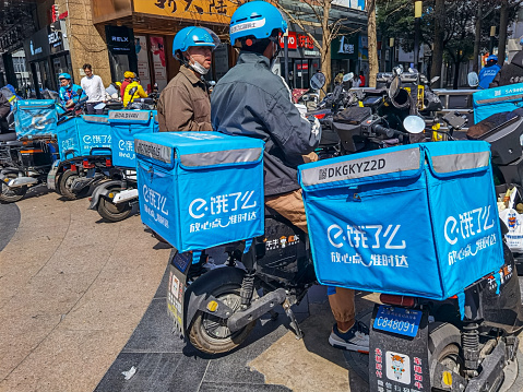 Shanghai, China- March 16, 2023: Ele. me food delivery riders sits on a street in Beijing. Ele.me is an online-to-offline (O2O) catering and food delivery platform owned by Alibaba Group in China.