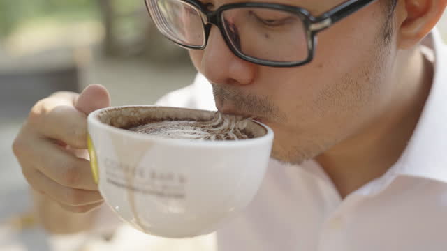 Slow motion close up of an asian man enjoying coffee
