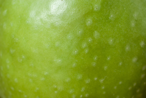 Macro photograph of the skin of a green apple.