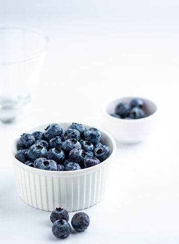 Fresh frozen Blueberries in a while bowl on a white background