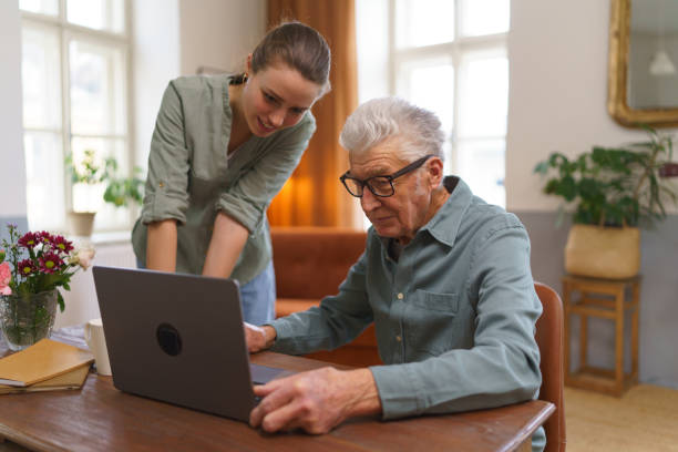 istock Granddaughter teaching grandfather how to use notebook. 1493827035