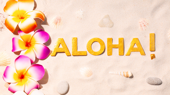 Aloha! - Hawaiian greeting and plumeria flowers in white sand
