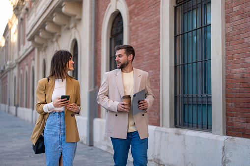 Young beautiful stylish woman and modern handsome man walking outside the building in town.
