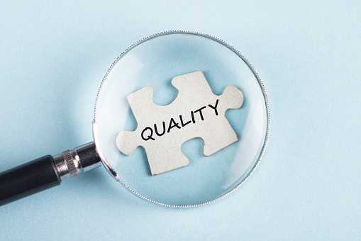 The word Quality on puzzle piece with magnifying glass