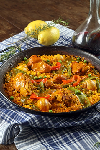 Valencian paella with porron of red wine on the wooden table
